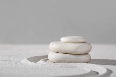 Gri duvarda çizgileri olan açık kumdaki spa taşları. Zen kavramı