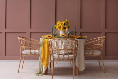 Tabaklar, mumlar ve güzel ayçiçekleri olan zarif bir masa.