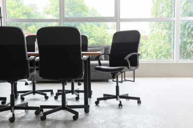 Konferans salonunda pencerenin yanındaki sandalyeli masa.