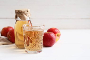 Şişe ile taze meyve ve beyaz ahşap arka planda bir bardak elma şarabı.