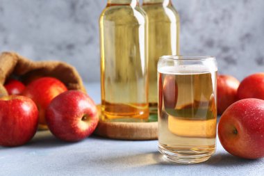 Gri grunge arka planında taze meyve, şişe ve bir bardak elma şarabı olan çuval.