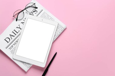 Tablet bilgisayarı ve pembe arka planda gözlüklü gazete.