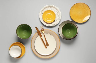 Gri arkaplanda temiz tabak, kase ve çatal bıçak takımı.