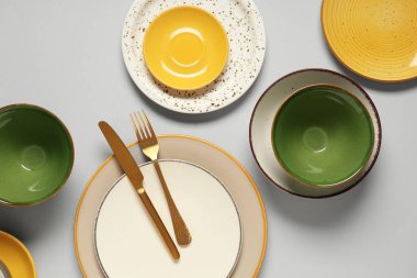 Gri arkaplanda temiz tabak, kase ve çatal bıçak takımı.