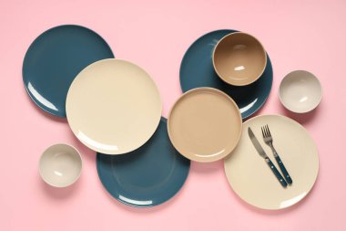 Pembe arka planda gümüş çatal bıçaklı farklı temiz tabaklar.