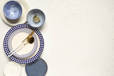 Beyaz zemin üzerinde altın çatal bıçak olan farklı temiz tabaklar.