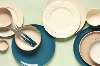 Yeşil zemin üzerinde gümüş çatal bıçak olan farklı temiz tabaklar.