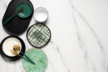 Beyaz zemin üzerinde altın çatal bıçak olan farklı temiz tabaklar.