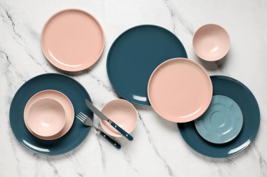 Beyaz zemin üzerinde gümüş çatal bıçak olan farklı temiz tabaklar.