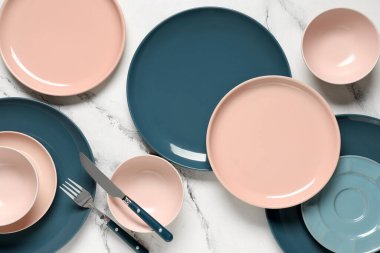 Beyaz zemin üzerinde gümüş çatal bıçak olan farklı temiz tabaklar.