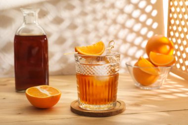 Bir bardak lezzetli, eski moda, portakallı kokteyl, ahşap masada, ışık duvarında.