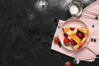 Lezzetli meyveli turta ve siyah grunge arka planda pudra şekerli tabak.