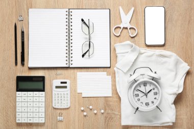 Şık okul üniforması, gözlüğü ve ahşap arka planda cep telefonu olan farklı kırtasiye malzemeleri.