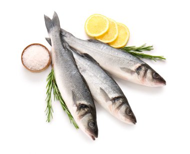 Taze deniz kabuğu balığı, limon dilimleri, biberiye dalları ve beyaz arkaplanda tuz izole edilmiş kase, yakın plan.