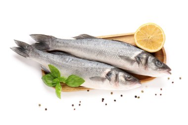 Beyaz arka planda taze deniz levreği, fesleğen yaprağı ve limon izole edilmiş, yakın plan.