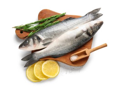 Taze deniz kabuğu balığı, limon dilimleri ve beyaz arka planda izole edilmiş biberiye dallarıyla kesme tahtası. Yakın plan.