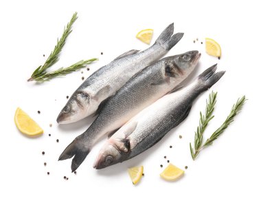 Taze deniz kabuğu balığı, biberiye dalları ve beyaz arka planda izole edilmiş limon parçaları, yakın plan.