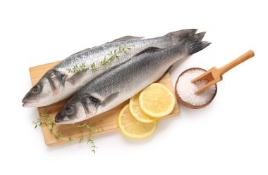 Taze levrek, kekik dalları ve limonlu tahta beyaz arka planda izole edilmiş, yakın plan.