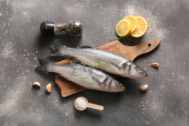 Taze çiğ deniz kabuğu balıklarıyla ahşap tahta tahta tahta ve koyu arka planda farklı baharatlar.