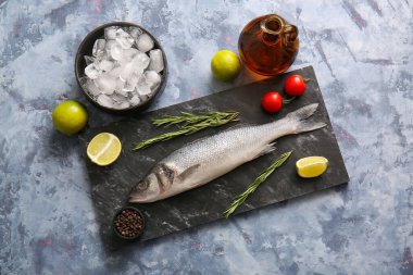 Taze çiğ deniz kabuğu balığı ve mavi arka planda farklı malzemelerle dolu bir tahta.