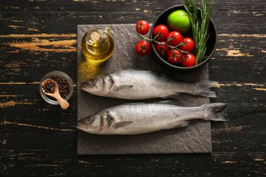 Taze çiğ deniz kabuğu balıkları ve siyah ahşap arka planda farklı malzemelerle dolu bir pano.