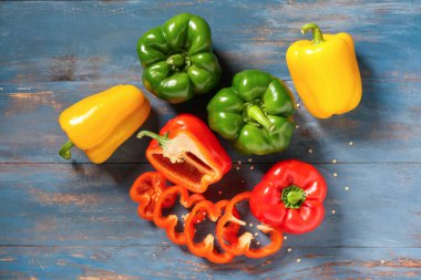 Mavi ahşap arka planda taze dolmalık biber ve tohumlar.