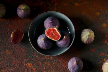 Koyu arkaplanda taze incirlerle dolu bir kâse.