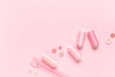 Düğmeli iplik makaraları ve pembe arka planda fermuar