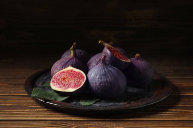 Kahverengi ahşap masada taze incir tabağı, yakın plan.