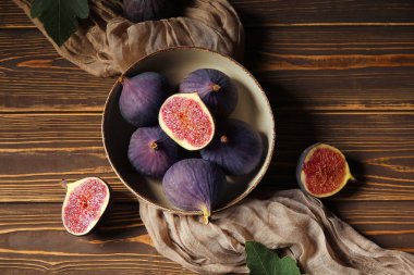 Kahverengi ahşap arka planda taze incir kabı, yakın plan.