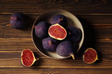 Kahverengi ahşap arka planda taze incir kabı, yakın plan.