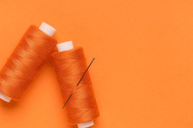 Turuncu zemin üzerinde iğne olan iplik makaraları