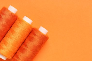 Turuncu arkaplanda iplik makaraları