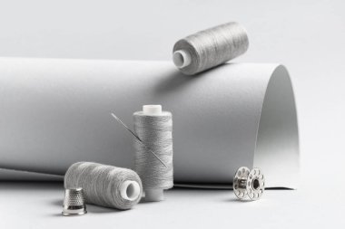 Gri arkaplanda iğnesi olan iplik makaraları