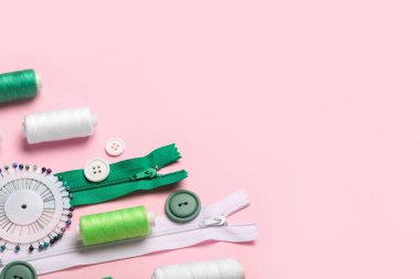 İplik makaralı, fermuarlı ve pembe arkaplanlı düğmeli kompozisyon, yakın plan