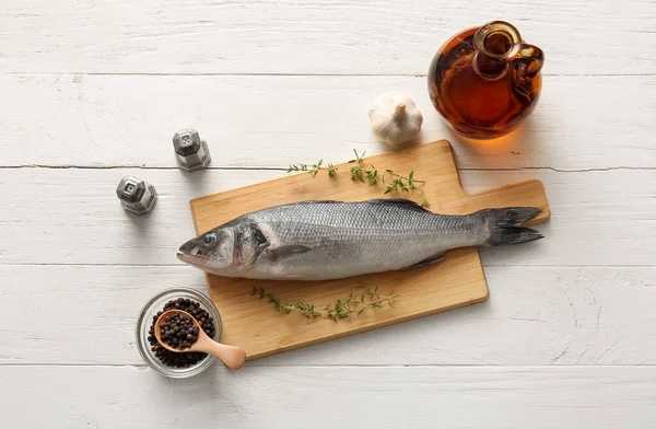 Taze çiğ deniz kabuğu balığı ve beyaz ahşap arka planda farklı baharatlarla kesilmiş tahta.
