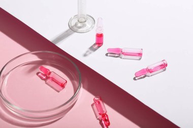 Glass ampoules with paper sheet on pink background