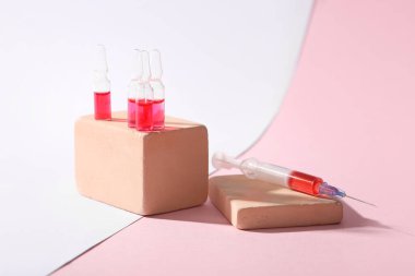Glass ampoules and syringe on color background