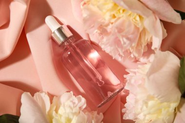 Kumaş zemin üzerinde şakayık çiçekleri olan bir şişe gerekli yağ.