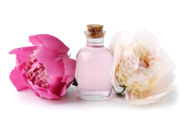 Beyaz arka planda güzel şakayık çiçekleri olan bir şişe gerekli yağ.