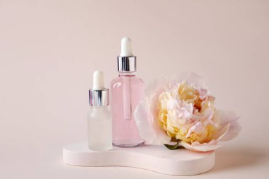 Gerekli yağ şişeleriyle sıva podyumu ve bej arka planda güzel şakayık çiçekleri.