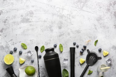 Limon parçalı farklı barmen aletleri, buz küpleri, gri arkaplanda kokteyl ve meyve sıkacağı.