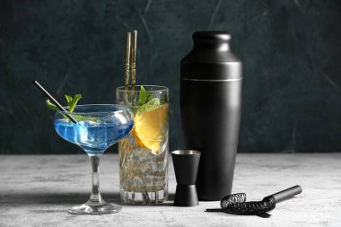 Barmen aletleri, yeşil grunge duvarına karşı gri masada farklı bardaklarda kokteyller.