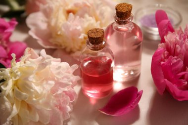 Bej arka planda şakayık çiçekleri olan gerekli yağ şişeleri.