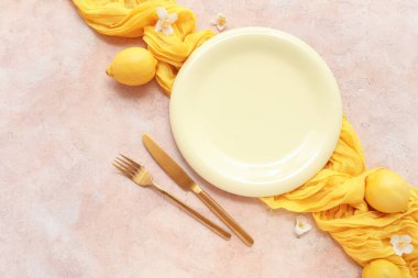 Tabak, çatal bıçak, peçete, yasemin çiçekleri ve bej renginde limonlu masa dekorları.