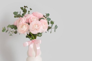 Beyaz arka planda güzel ranunculus çiçekleri olan vazo, yakın plan.