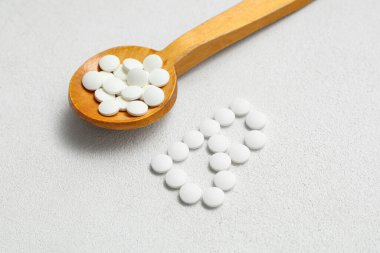 Beyaz arka planda B vitamini hapları olan tahta kaşık.