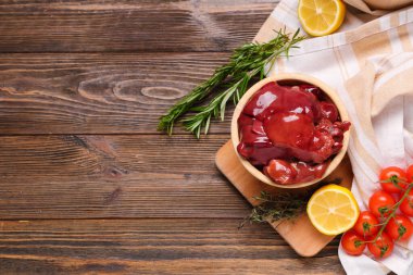 Biberiyeli çiğ ciğer, domates ve ahşap arka planda limon.