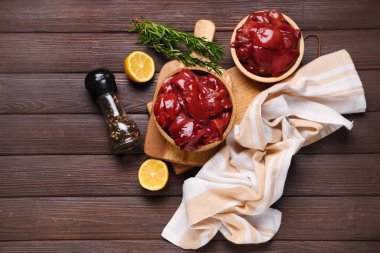 Biberiyeli çiğ ciğer ve ahşap arka planda limon.