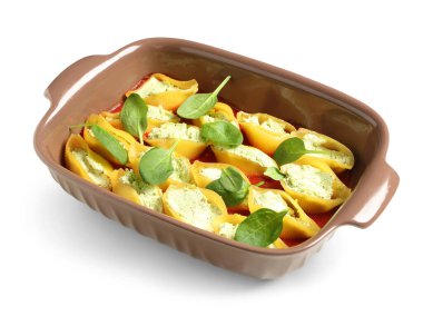 Beyaz arka planda ricotta, domates sosu ve ıspanakla doldurulmuş koni makarnası pişirme.